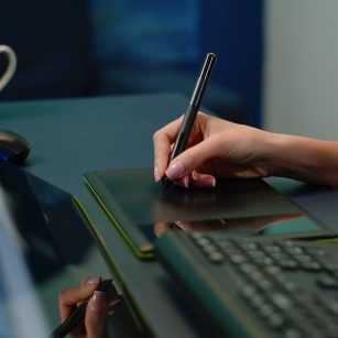 Close up of hand holding stylus on graphic tablet for retouch work Close up of hand holding stylus on graphic tablet for retouch work. Woman photographer using editing app for pictures retouching at photography studio. Image editor with devices